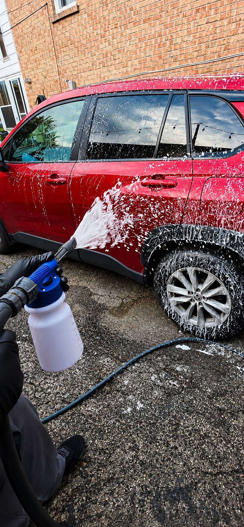 Scrub Bros foaming a red SUV by hand in a Toronto driveway